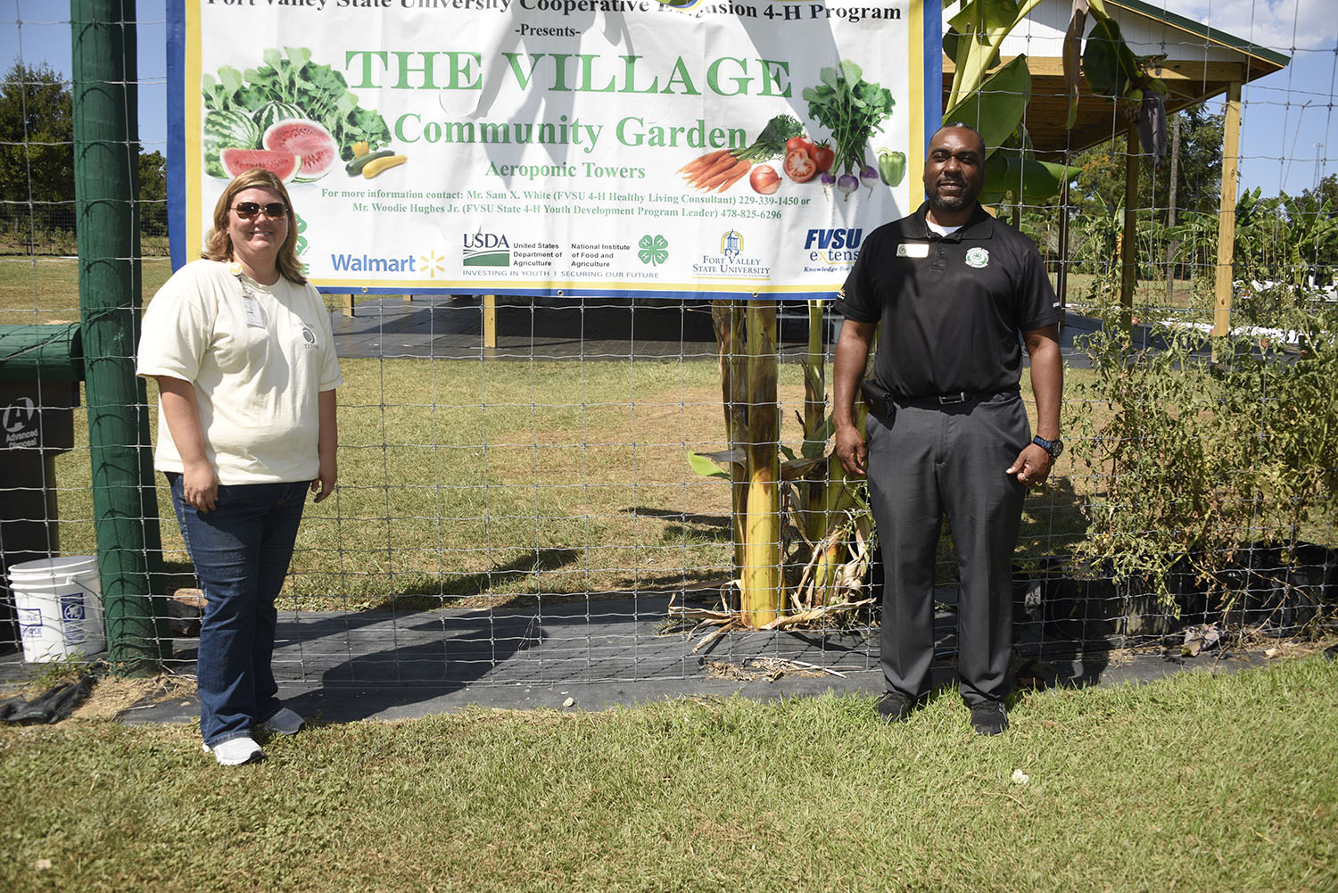 Pam Parten (left), STEM chairperson for Worth County Middle School and Woodie Hughes Jr., FVSU assistant Extension administrator and 4-H program leader, pose in front of Village Community Garden sign in Sylvester.