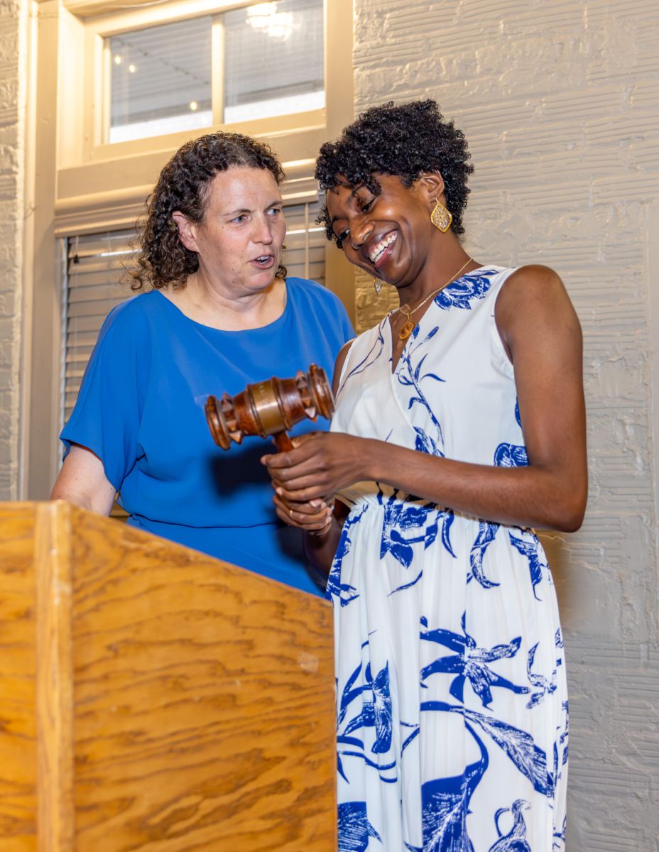 Two people holding gavel at a podium