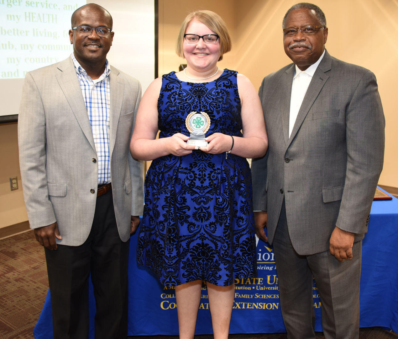 Phillip Pettway, Fort Valley State University 4-H Twiggs County Extension agent (left)  and Dr. Mark Latimore Jr., FVSU Extension administrator (right), present Madison Williams, an eighth-grader from Houston County, a first place award in poster competition during the closing ceremonies of 4-H Expo Week on March 22.